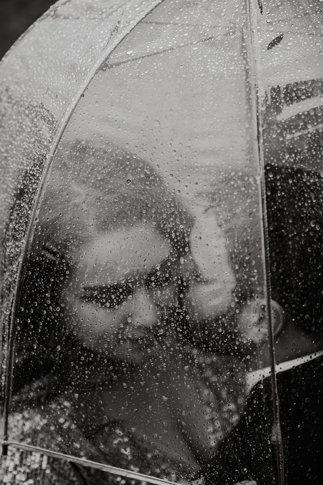 bride and groom kissing under an umbrella in the rain in alaska