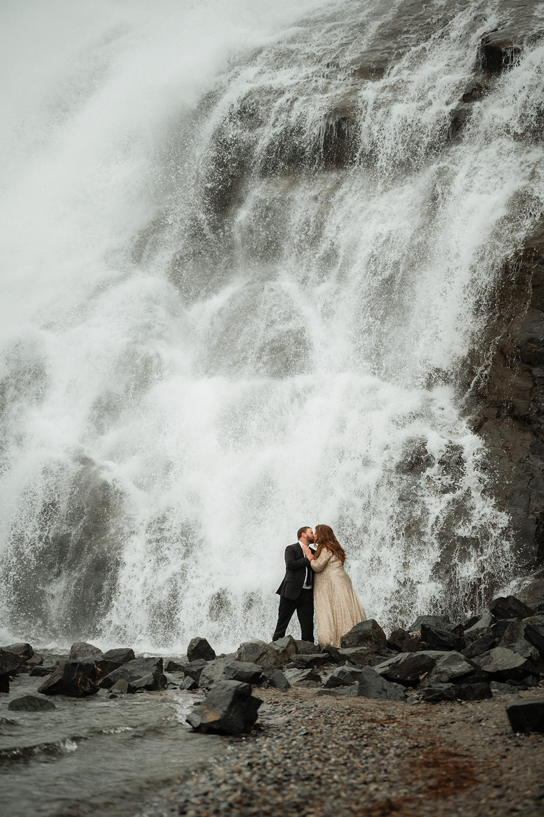 moody and cinematic bridal portraits in front of a waterfall in alaska.