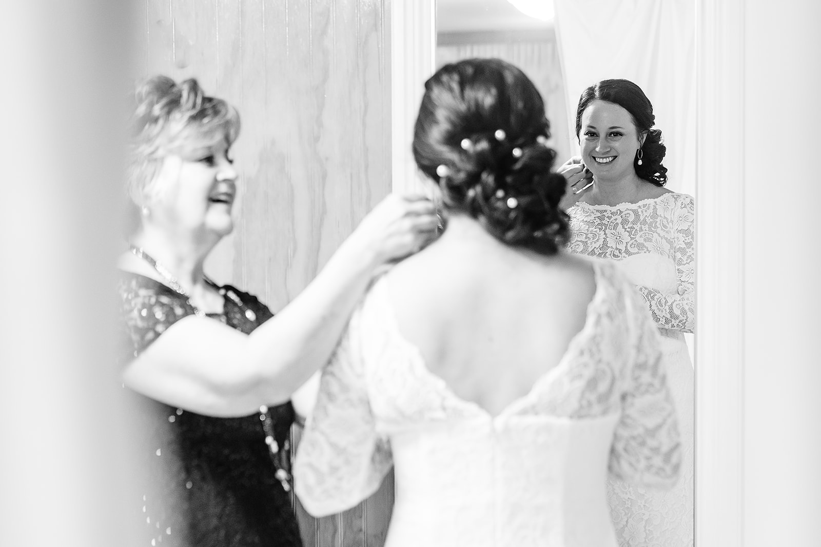 mother of the bride helps bride put on earrings at port gamble wedding