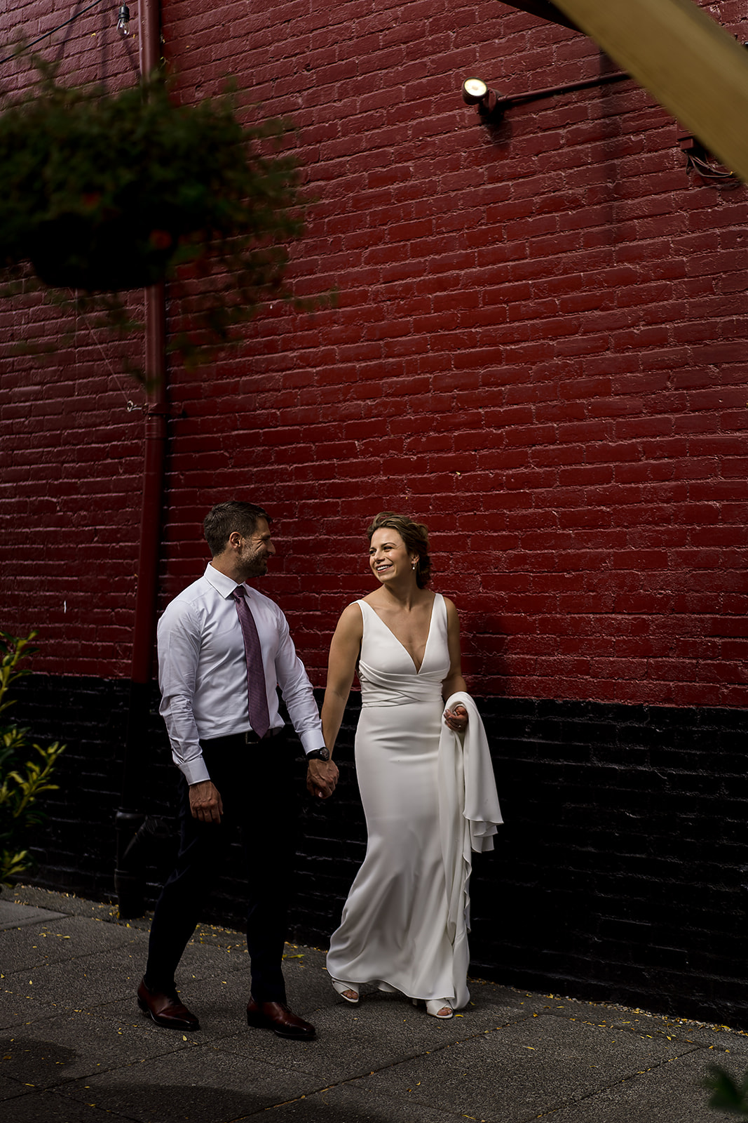couples walks through Ballard by red brick wall