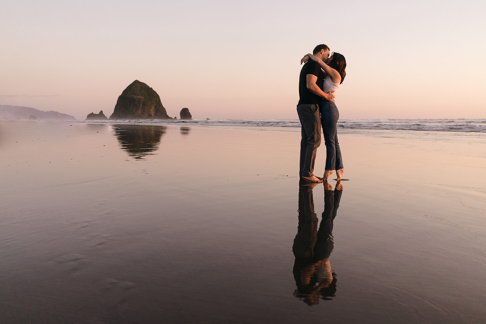 reflection of couple kissing with haystack rock in the background during Cannon Beach Engagement session