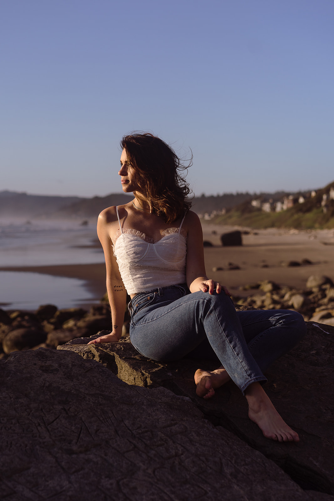 female portrait at Cannon beach posed on beach rocks