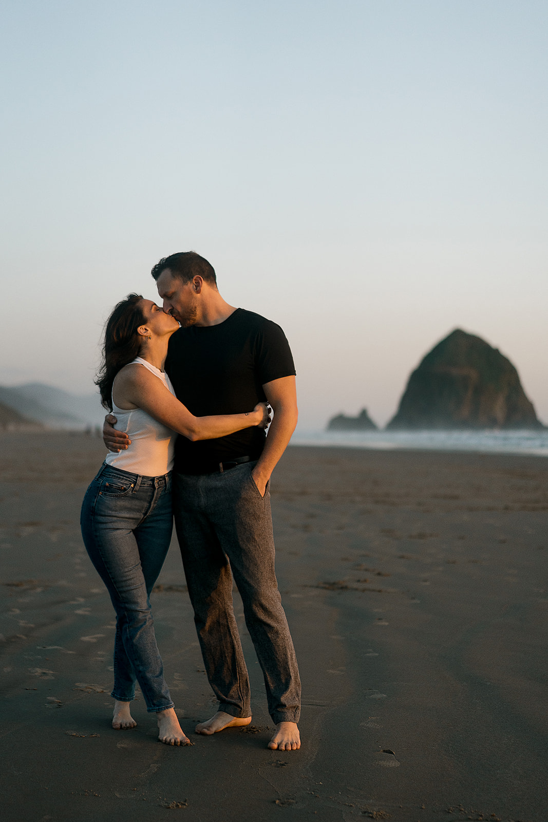 couple kisses in from of Haystack rock during Cannon Beach Engagement session