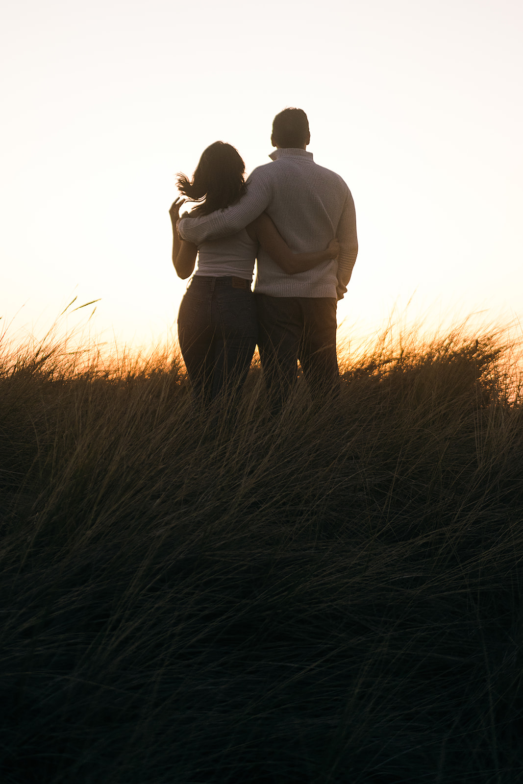 couple watches the sunset on the Oregon Coast during their Cannon Beach Engagement session