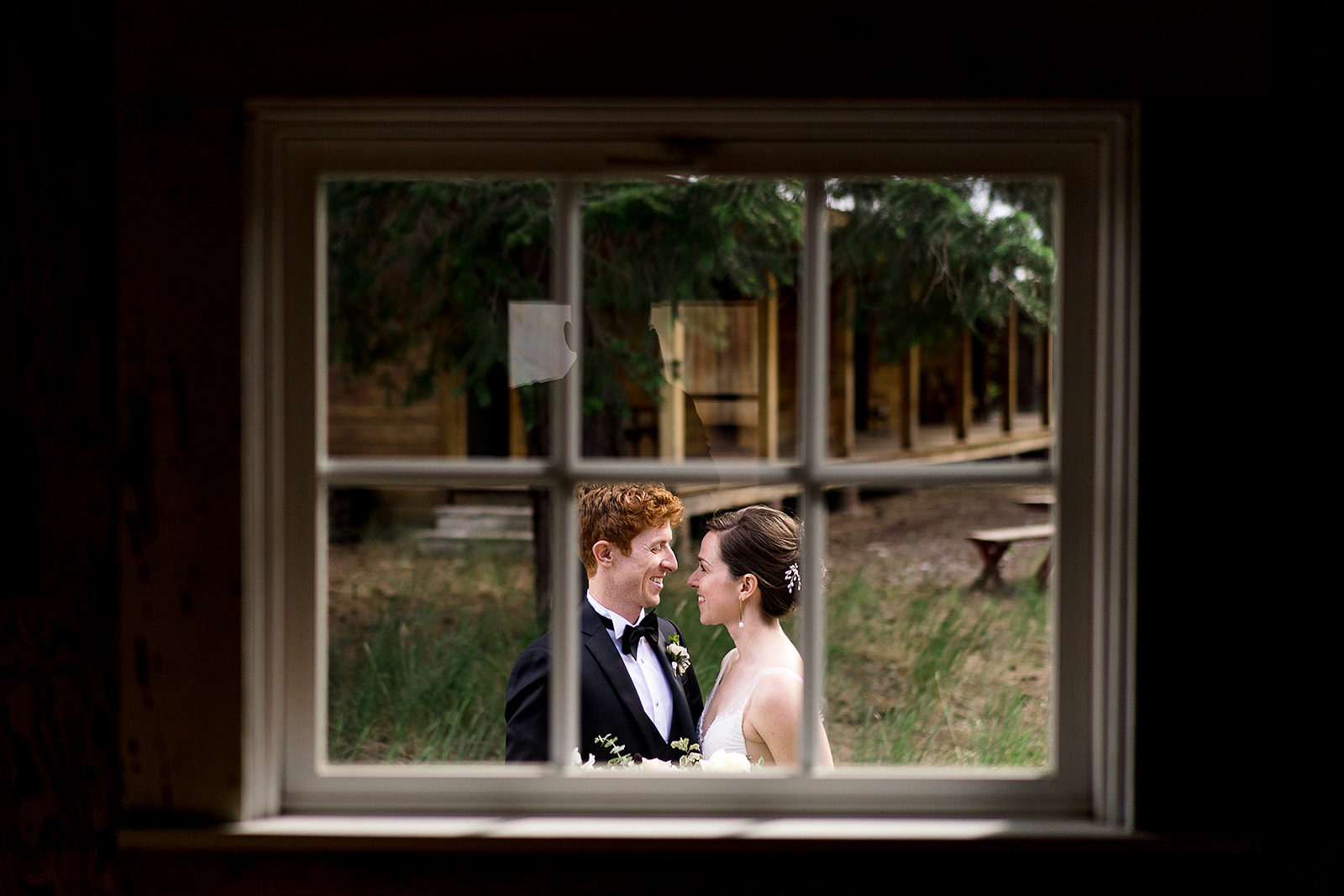 bride and groom wedding portrait photographed through barn window at Mazama Ranch House Wedding ceremony