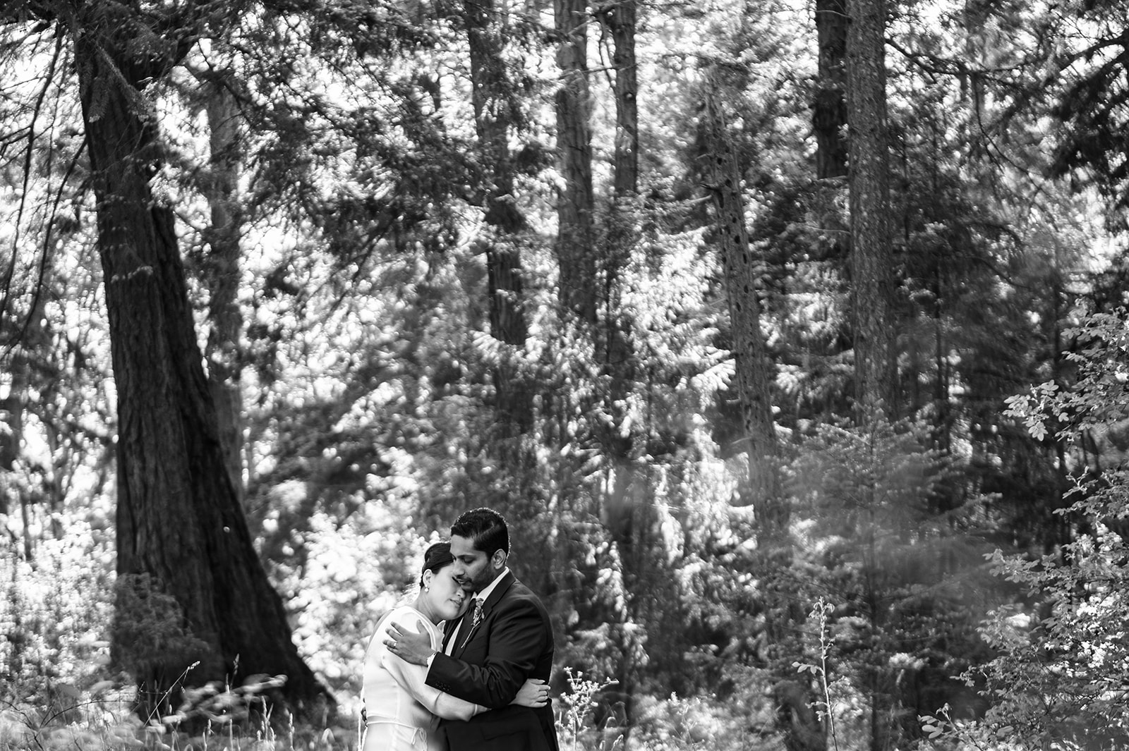 Black and white photo of Bride and Groom cuddling in the grasses at Rathtrevor Beach