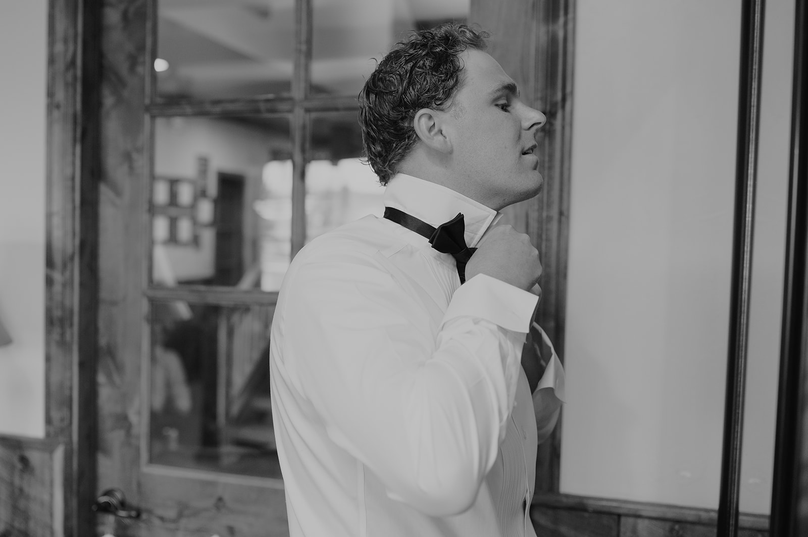 Groom fixing his tie as he gets ready.