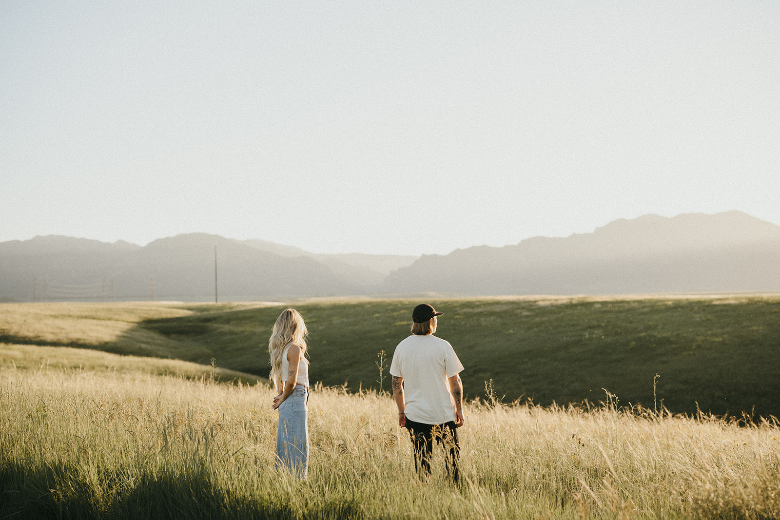Engagement session in a big open field mountains in the background, unique couples session inspiration. 