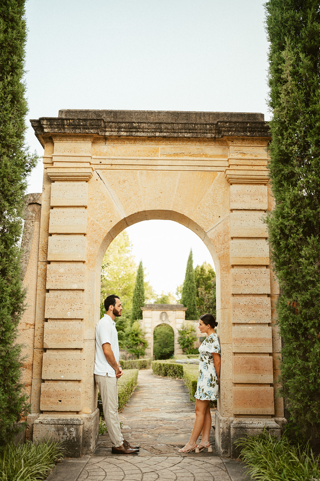 couple leaning against arch on the grounds of philbrook museum