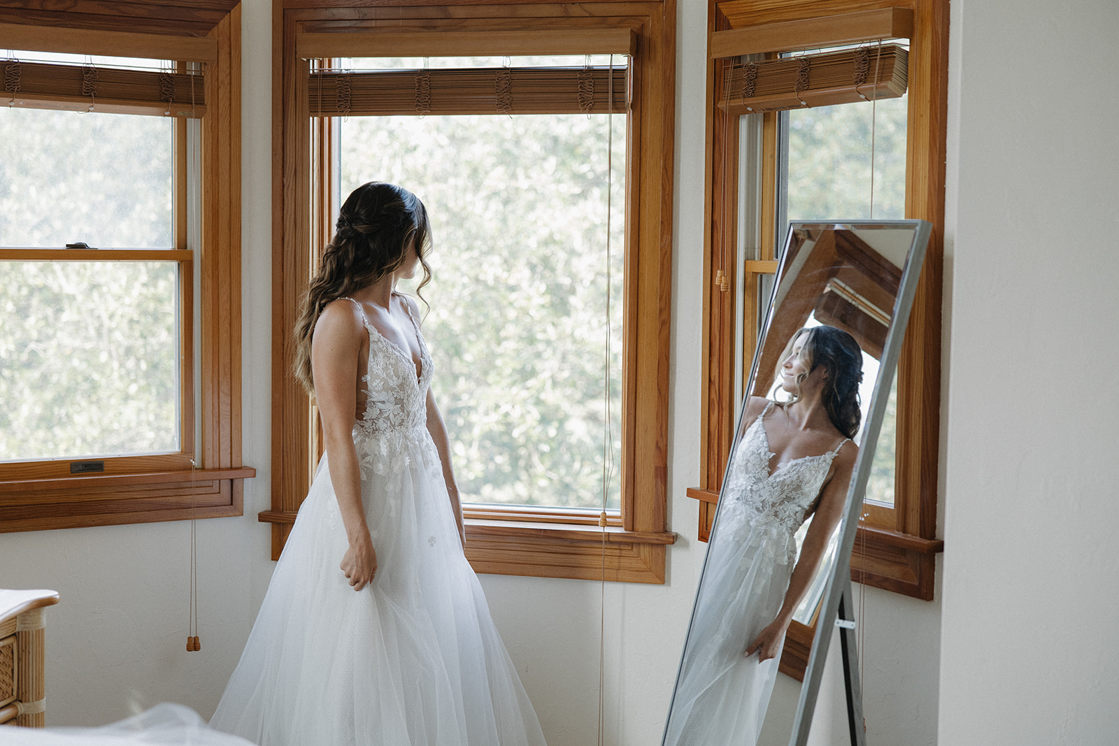 bride looks at dress in mirror
