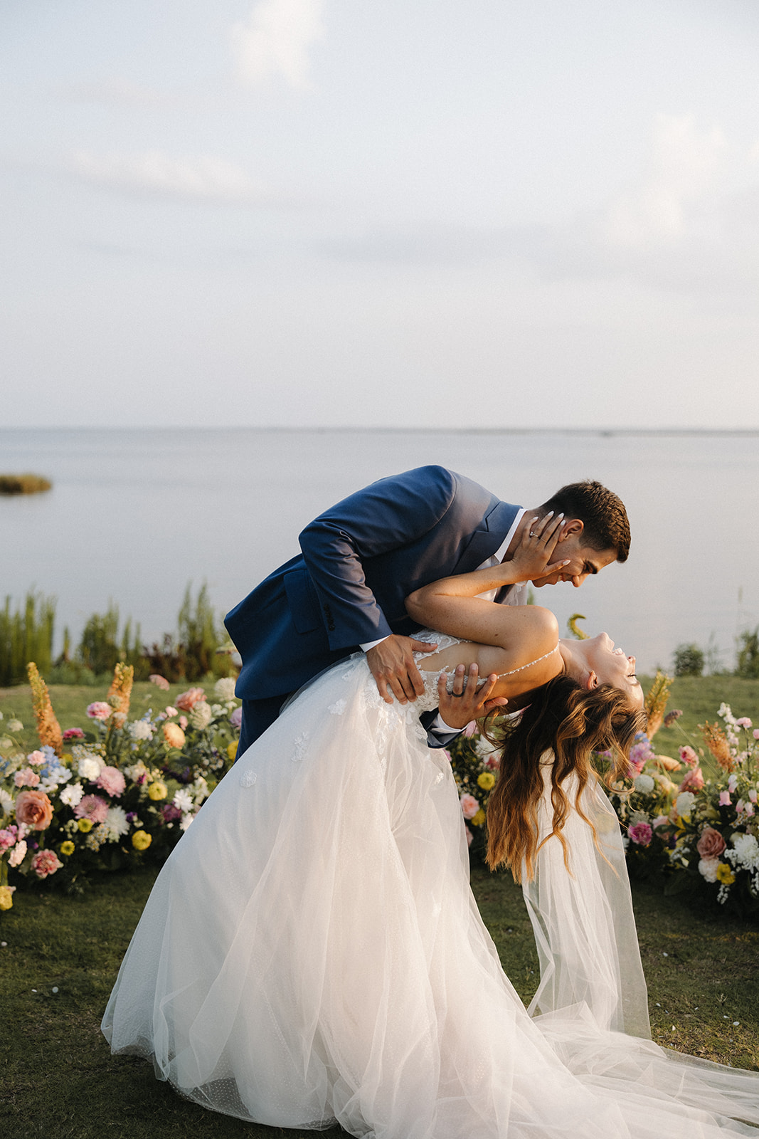 couple embraces beside wedding flowers