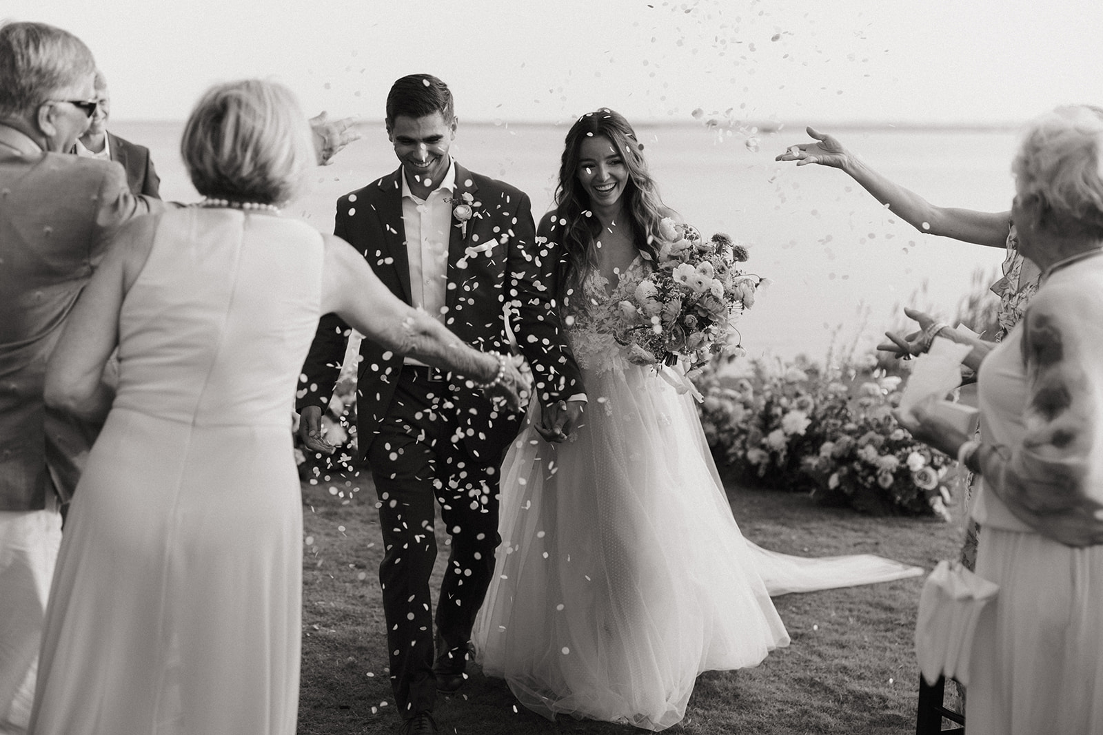 couple exits wedding with flower petals tossed on them