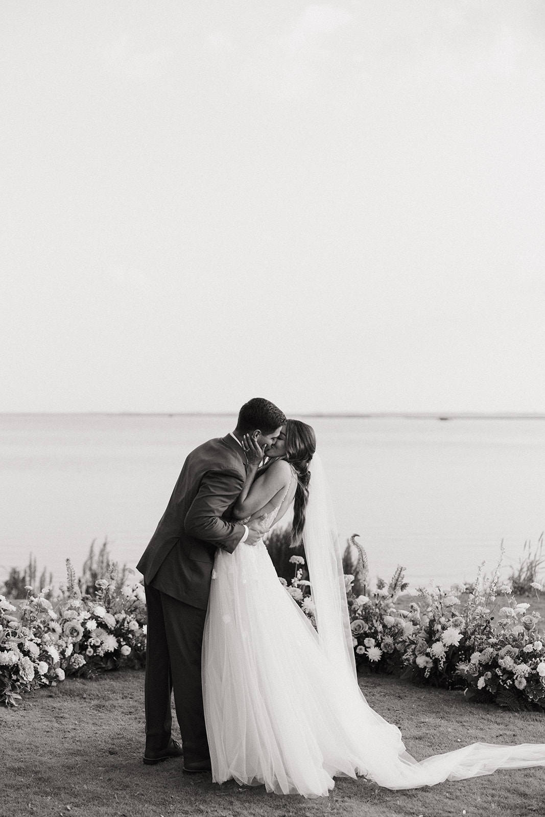 couple kisses beside wedding florals