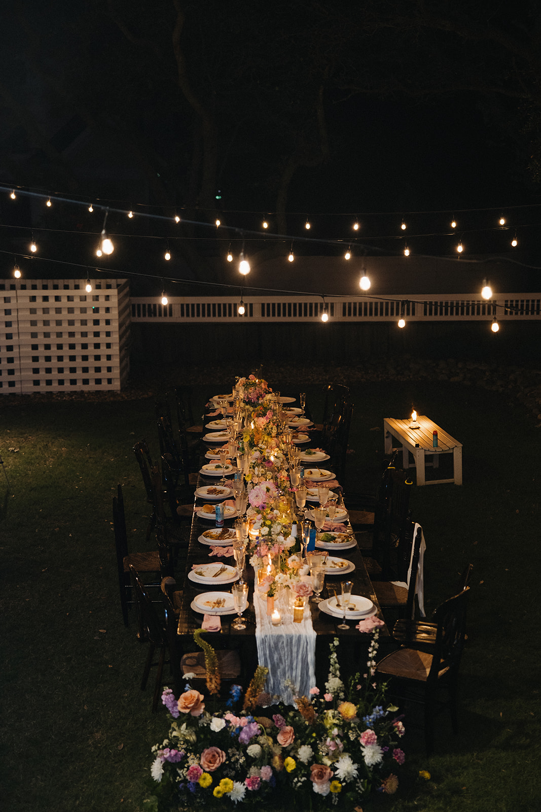 floral decor on long table with lights at backyard wedding reception