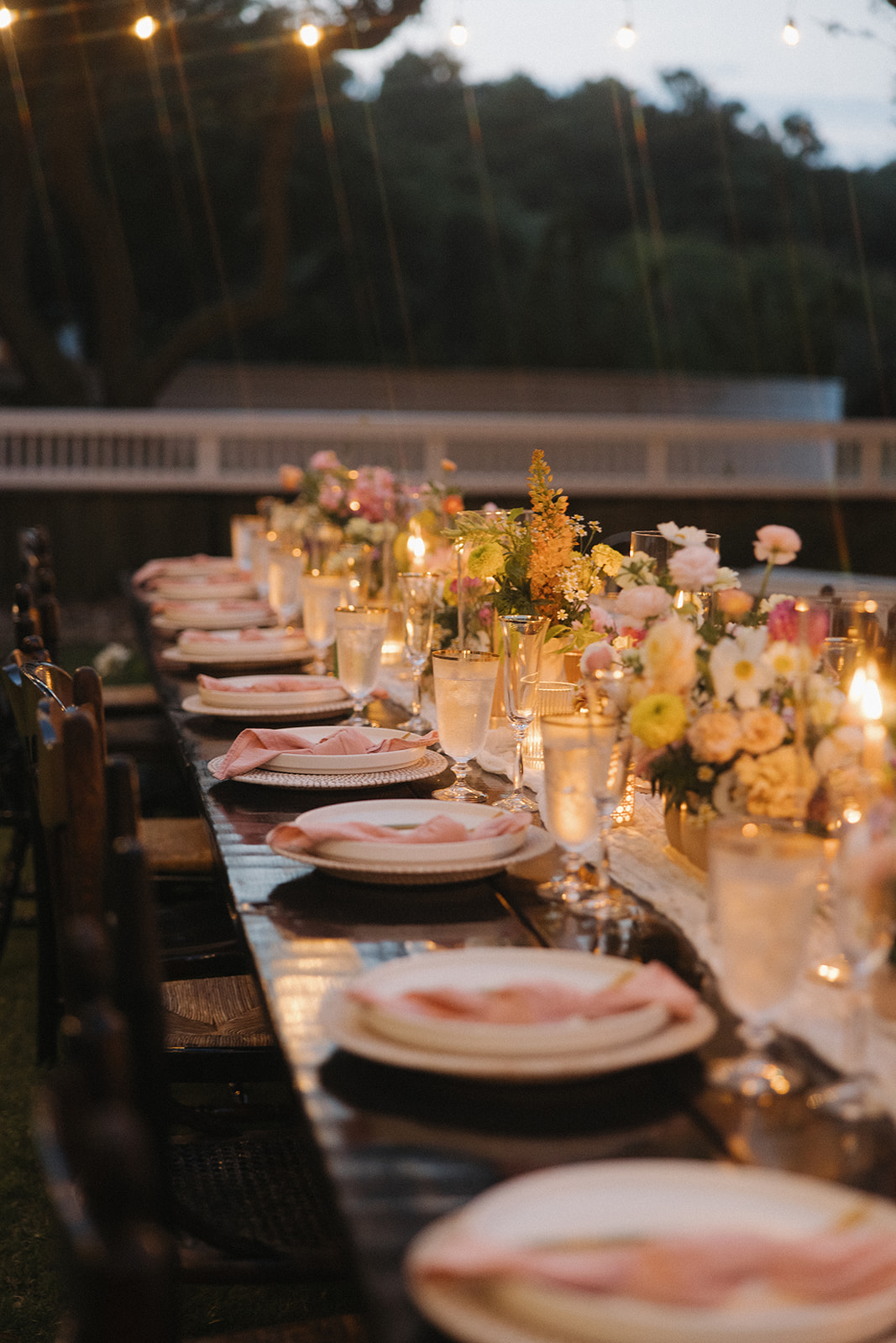 floral decor on long table with lights at backyard wedding reception