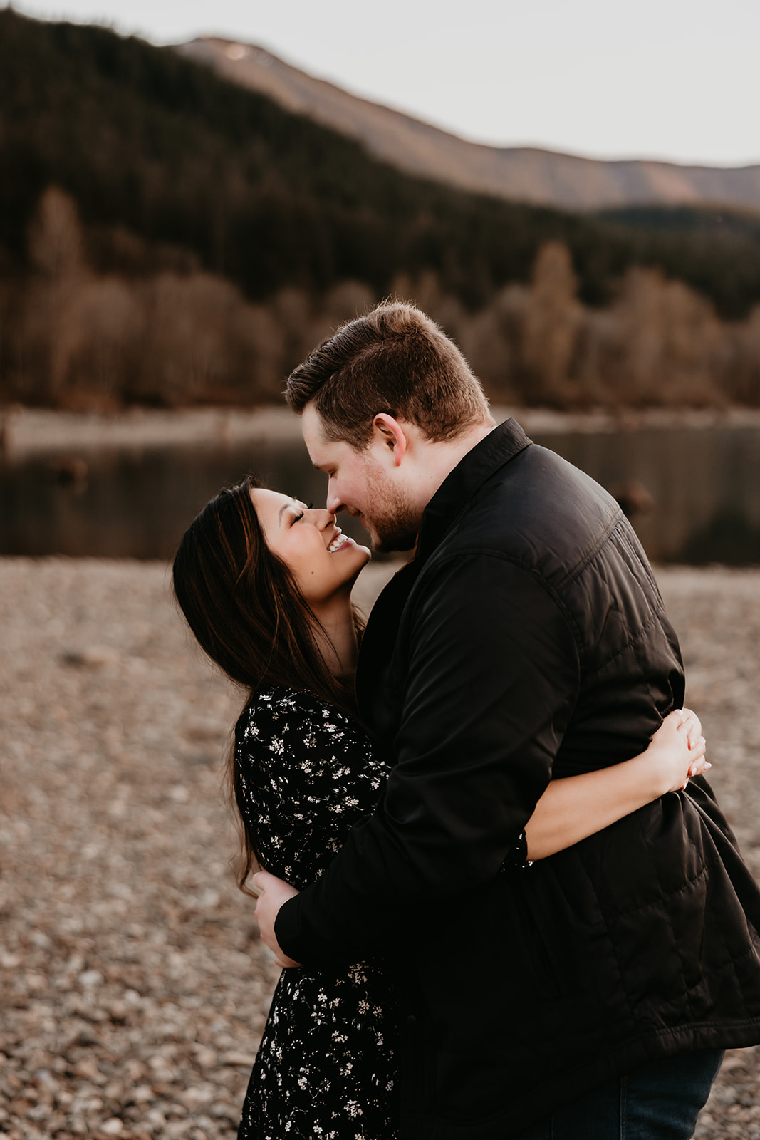A romantic couple standing close to each other, embracing, against the backdrop of a vibrant sunset at Rattlesnake Lake
