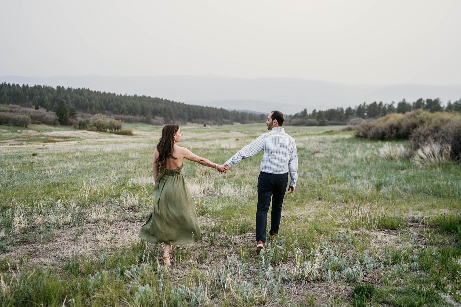 A couple dancing around in a beautiful mountain meadow with stunning views at Dawson's Butte in Castle Rock, Colorado