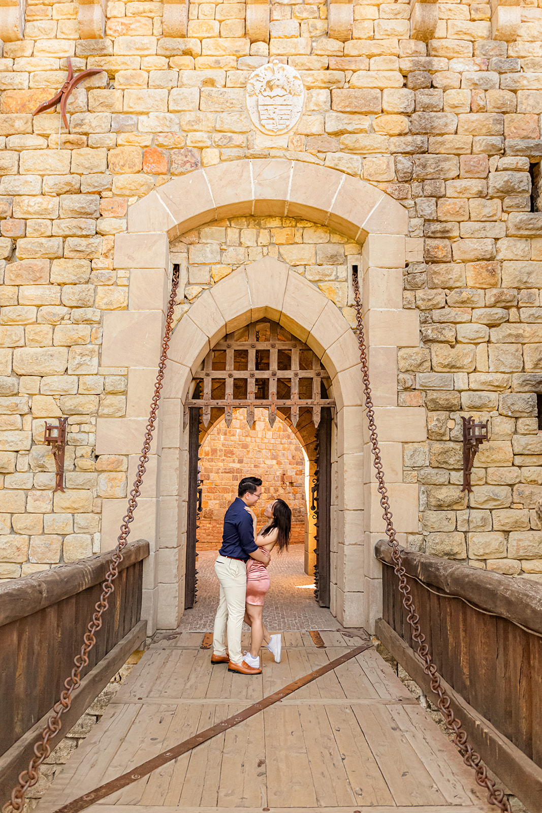 nonbinary person and their fiancée in front of a castle drawbridge