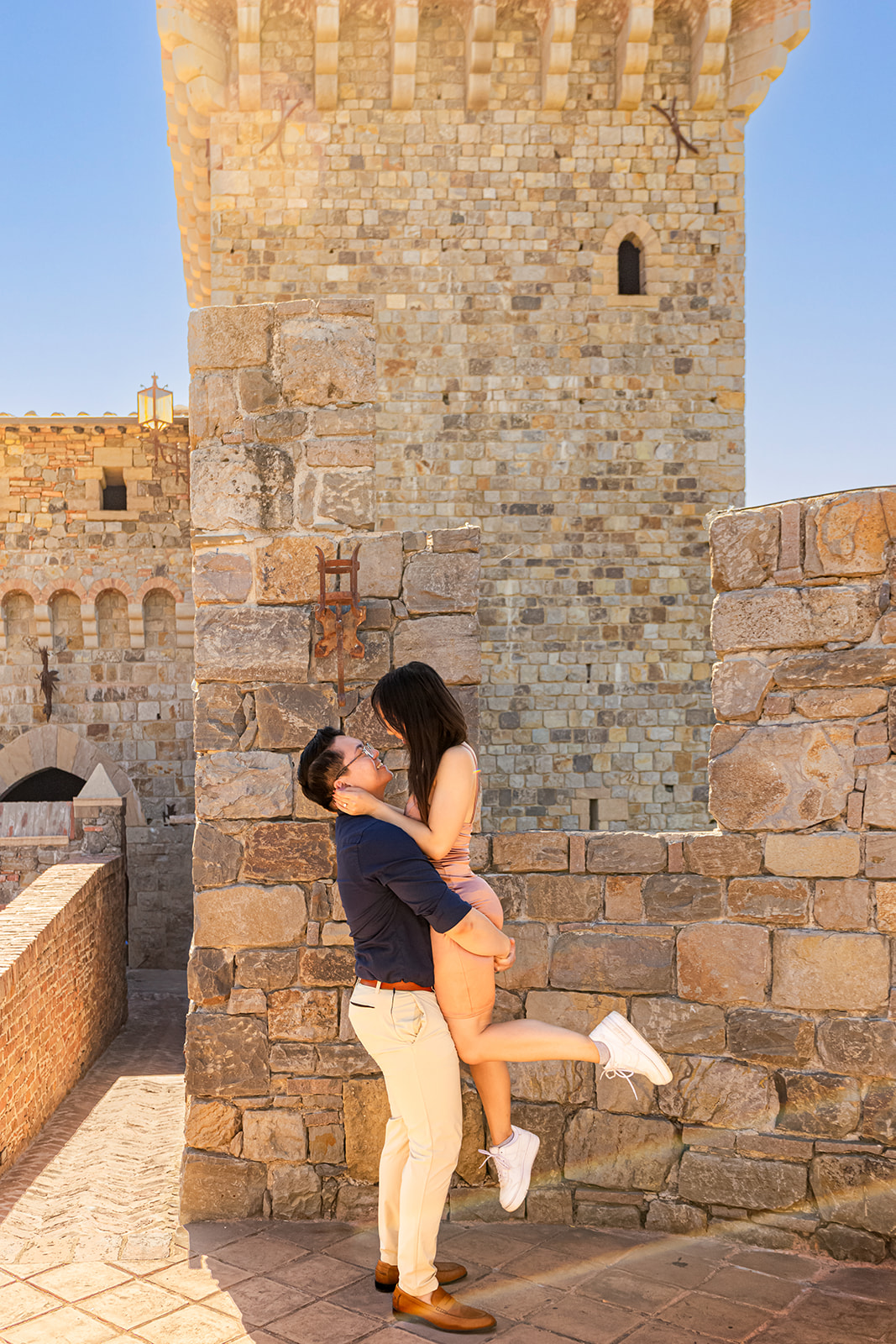 nonbinary person and their fiancée in front of a castle turret