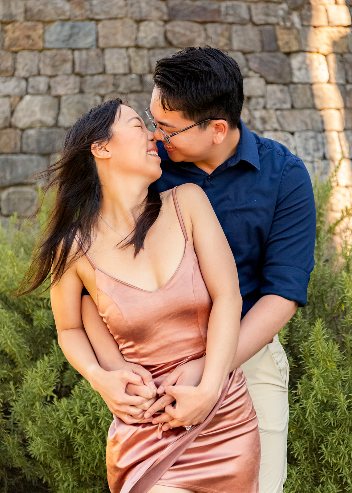 nonbinary person and their fiancée kissing in front of a castle winery