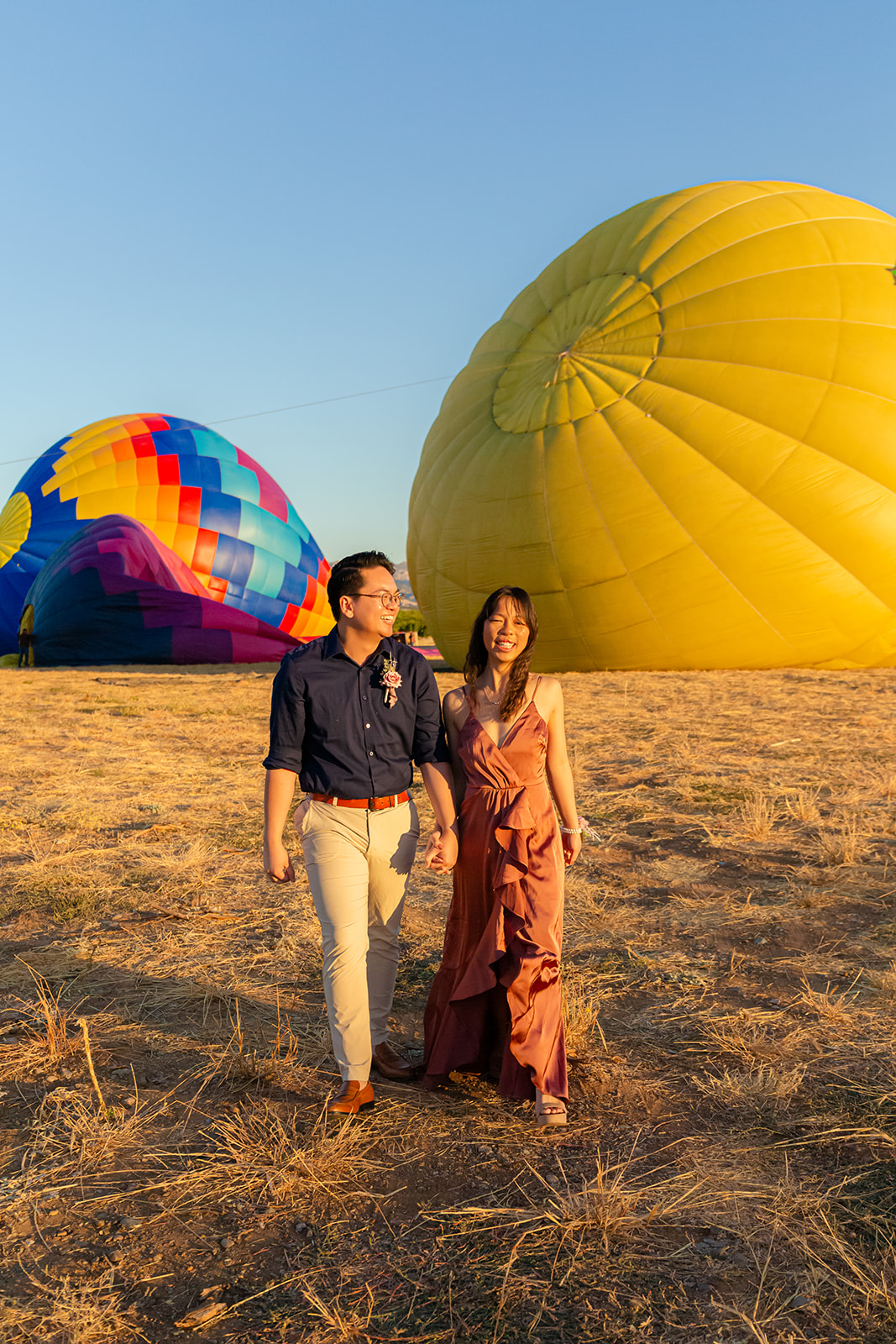 nonbinary person and their girlfriend walking in front of colorful hot air balloons