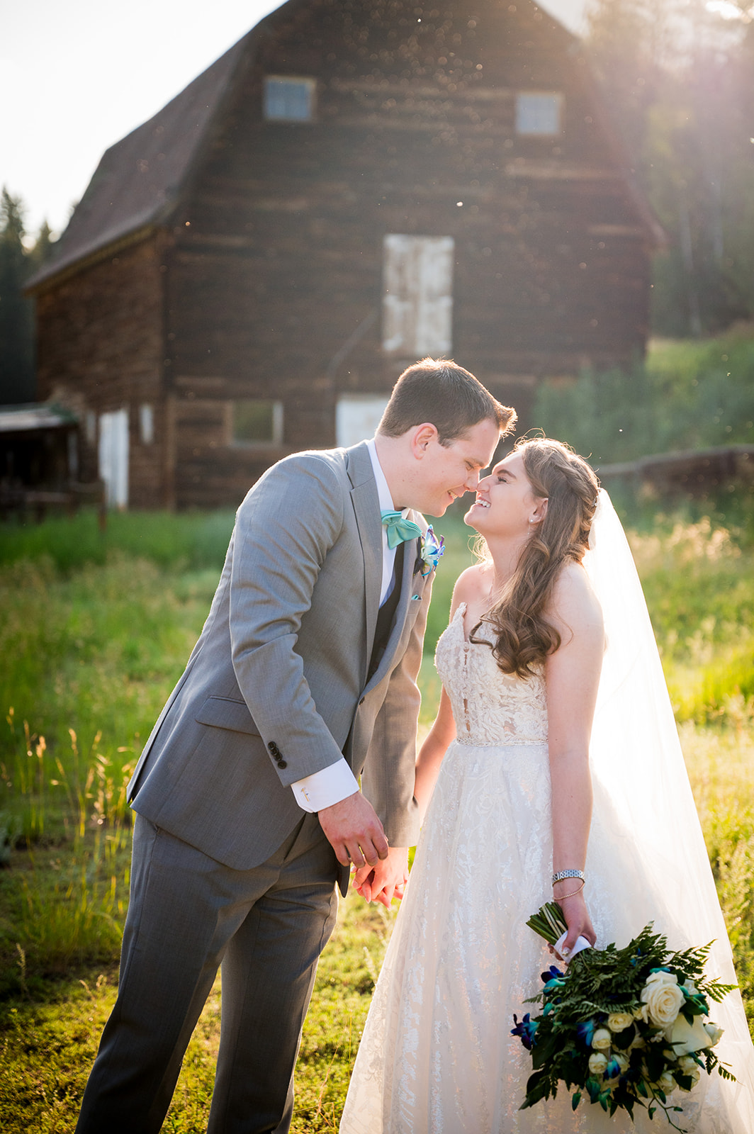 The groom leans in and shares eskimo kisses with the bride as the golden hour sun shines behind them.