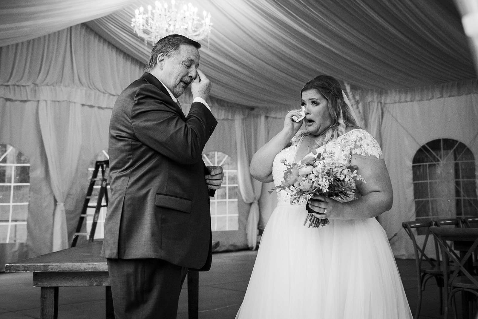 The bride and her father wipe tears from their eyes after sharing a first look on her wedding day.