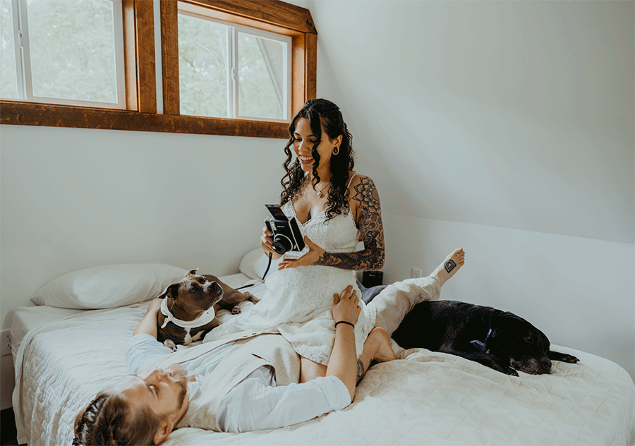 A couple on their elopement day lay in bed and take Polaroids pictures of each other