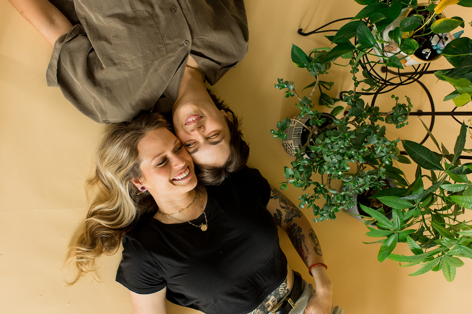 A Couple lies on floor with their heads together looking at the camera. 