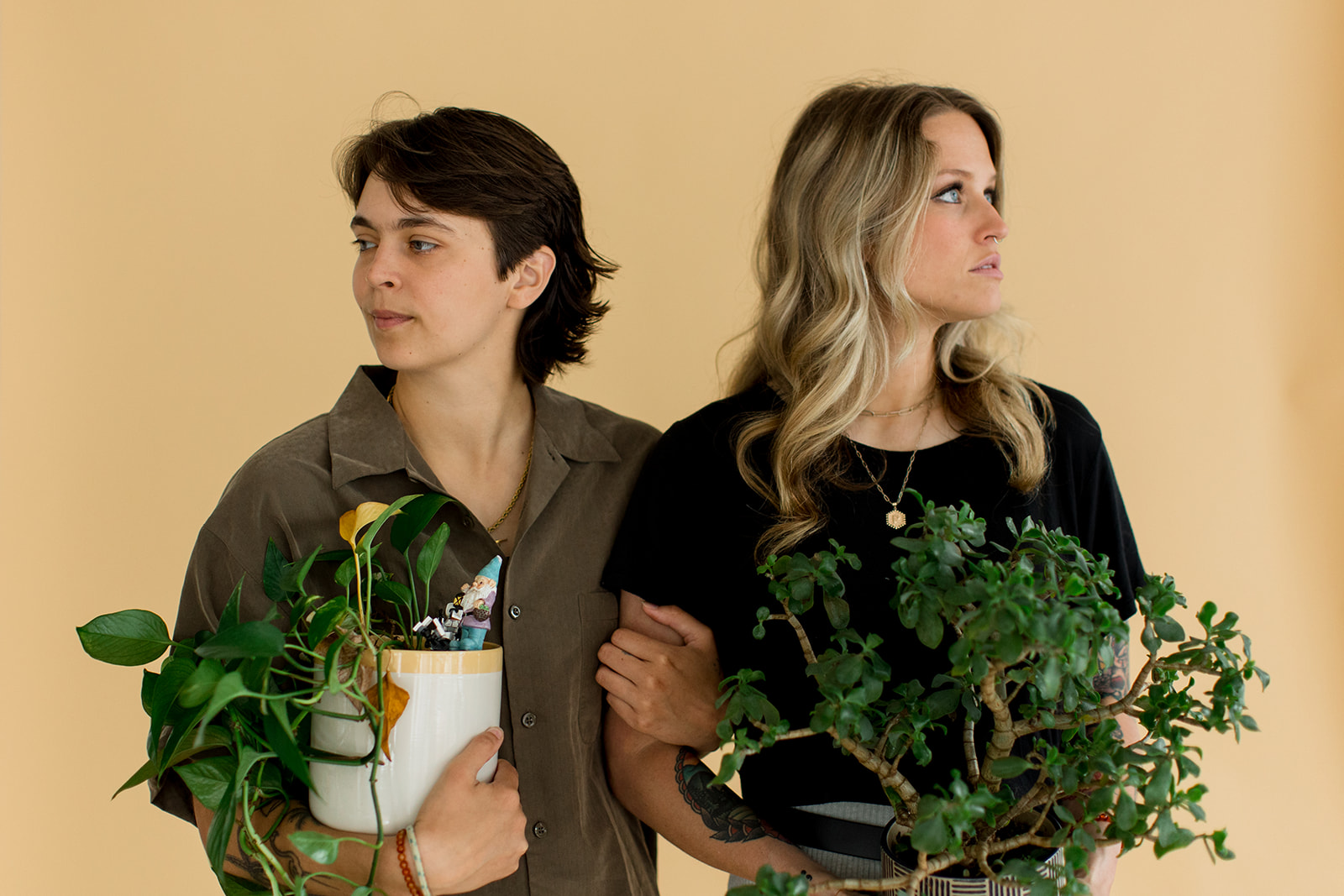 A couple looks in opposite directions while holding their beloved houseplants for a creative photo
