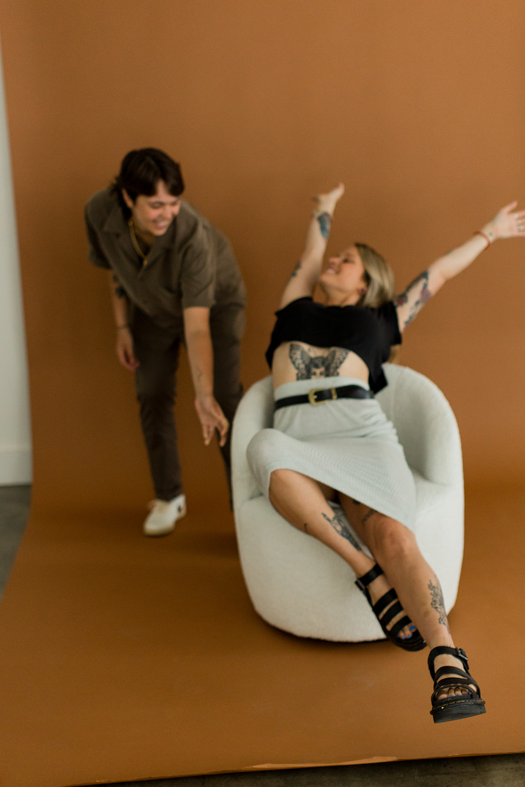 A couple playfully spin each other in a turning chair for a fun candid photo