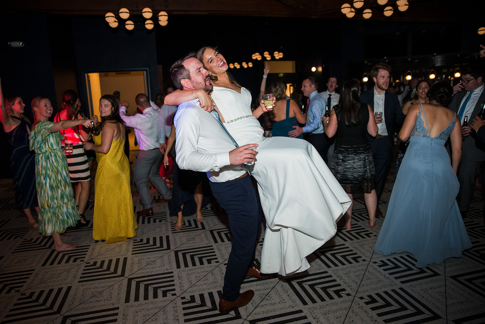 Groom lifts bride up and spins her around at their wedding reception.