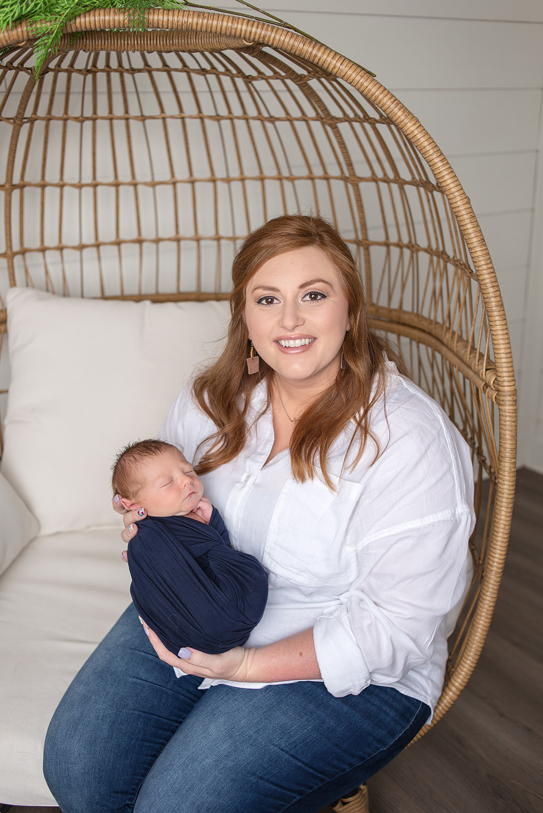 Newborn boy in Celesta Champagne Photography studio in Carthage, Missouri with his mom in a rattan egg chair snuggled up