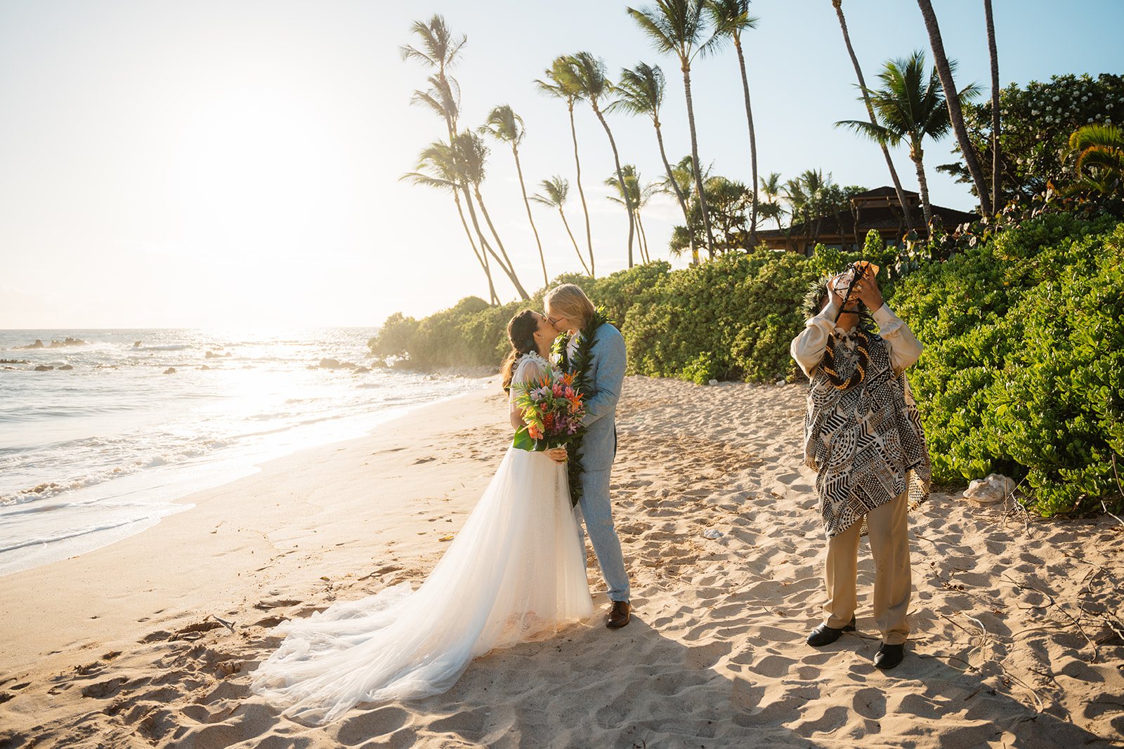 A couple kisses during their Maui beach wedding at on White Rock beach