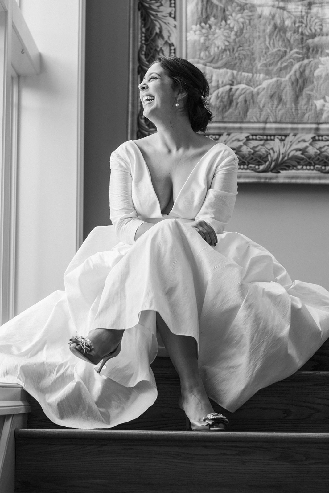 Bride smiling and sitting in stairwell of private residence ahead of backyard wedding