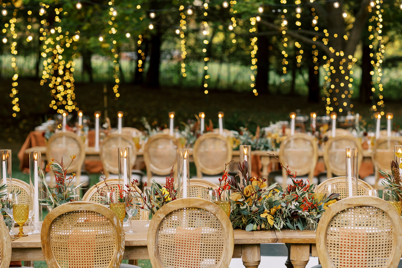 Stunning backyard wedding reception details of table setting with hanging string lights from trees in Maryland
