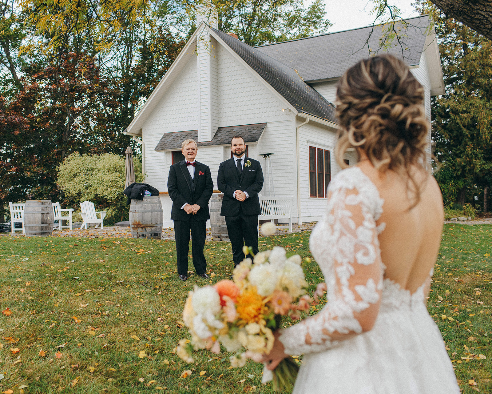 A groom and dad look genuinely and lovingly at the bride on a rainy wedding day in Traverse City, Michigan