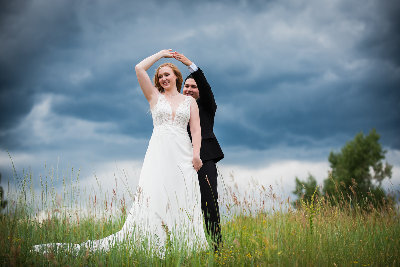The groom twirls the bride in an open field.