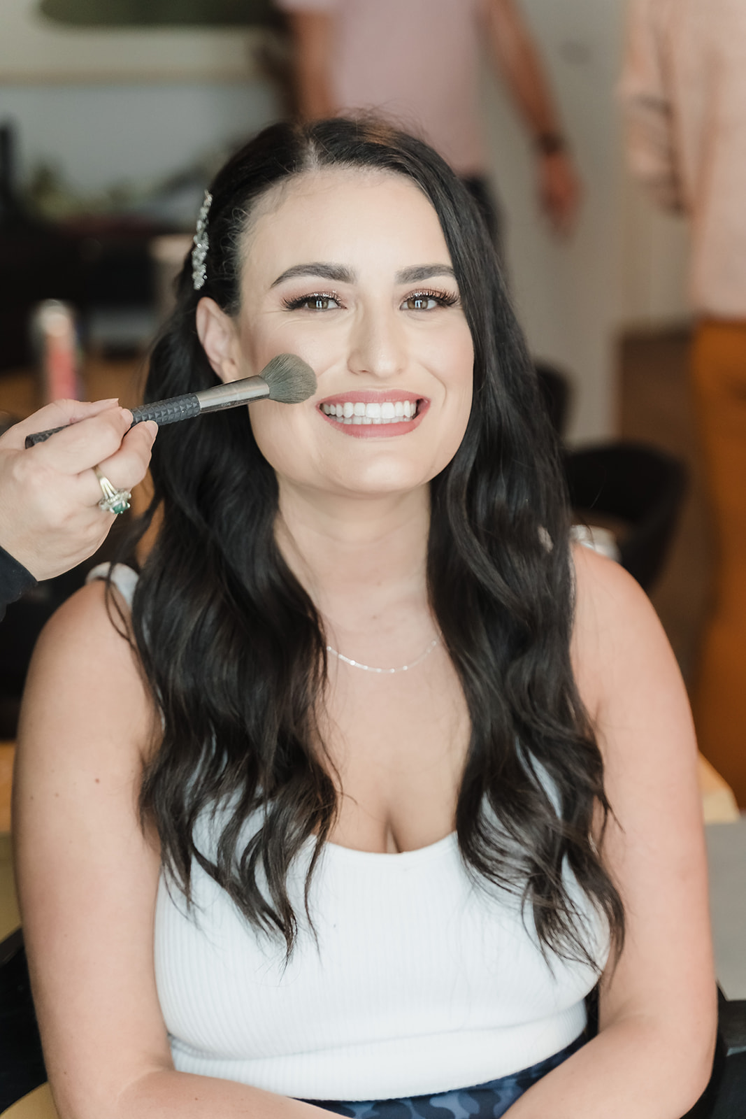 bride smiles while getting makeup done
