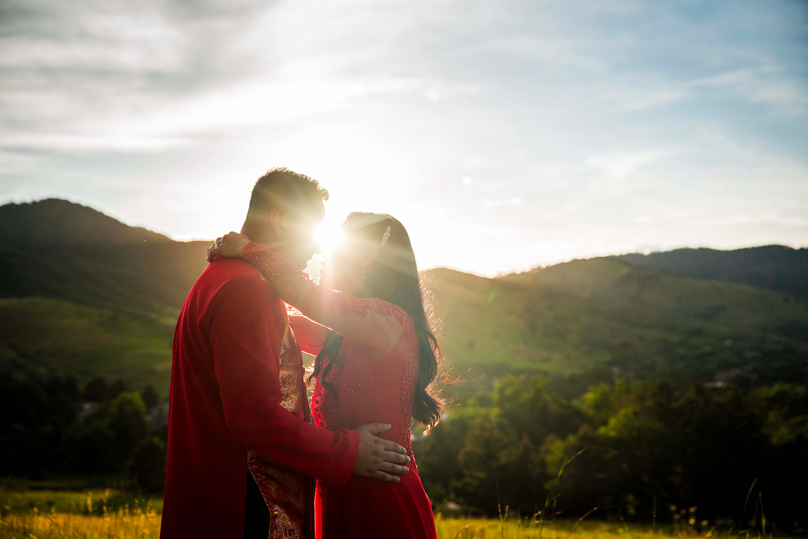 Bride and groom give eskimo kisses during golden hour in traditional Vietnamese outfits.