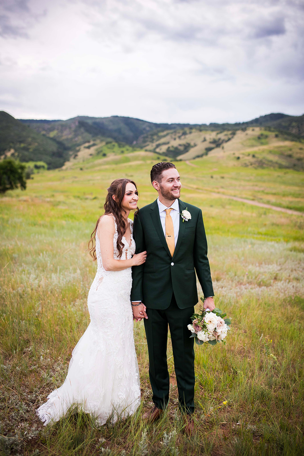 The bride and groom look off into the distance with the Colorado landscape in the background.