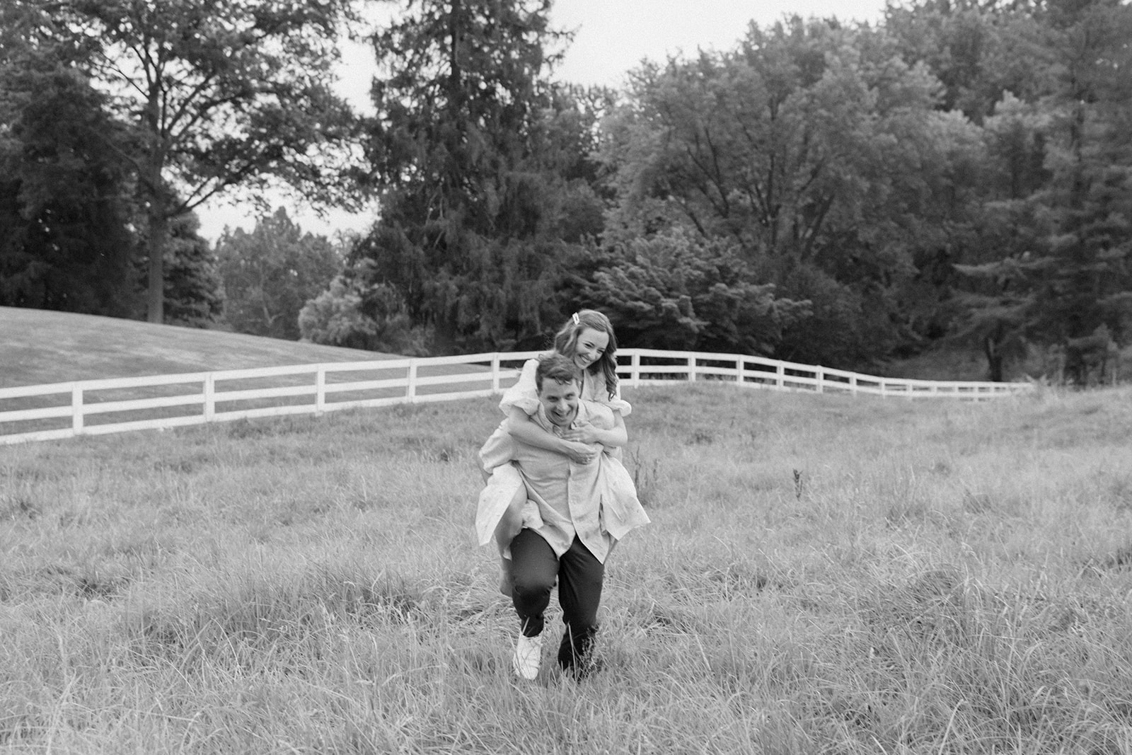 Engagement session piggy back ride through a field.