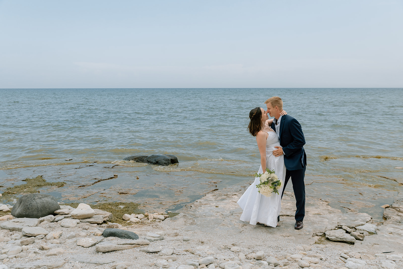 Bride and groom kiss in front of Lake Michigan