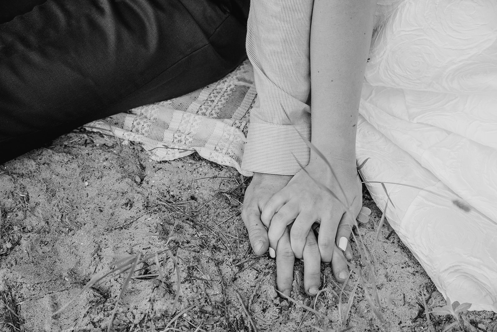 Couple holds hands on the beach in black and white image