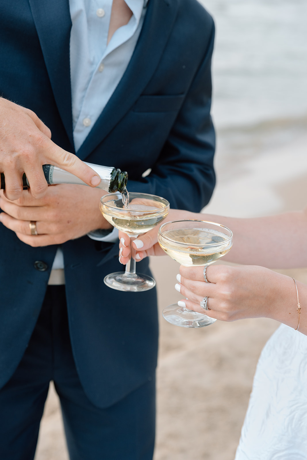 Groom pours champagne for his wife on the beach in Door County