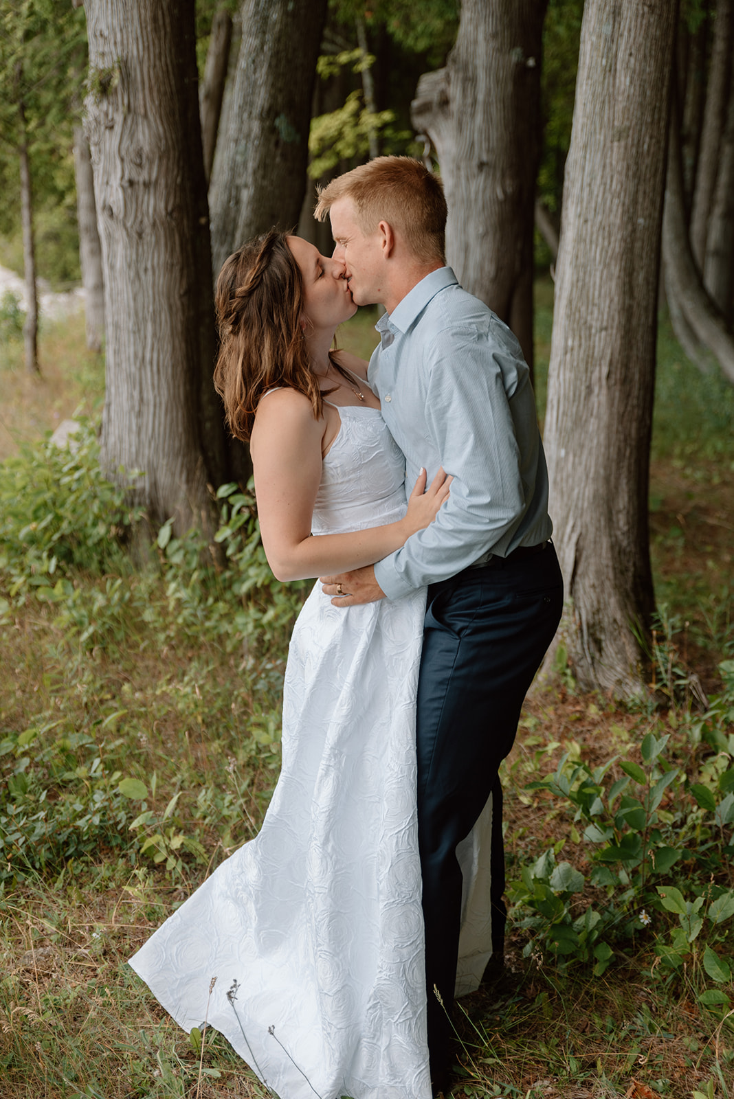 Husband and wife share a kiss among the Door County cedars