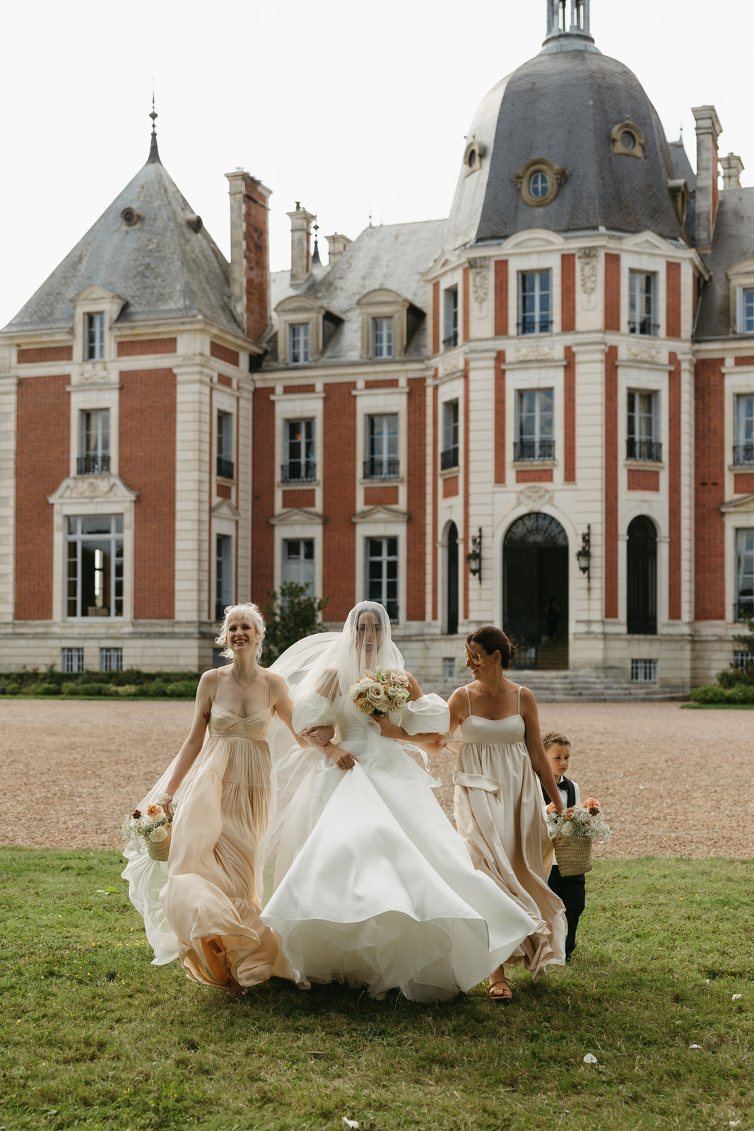 Bride and her two sisters walking down the chateau steps to her ceremony under an oak tree