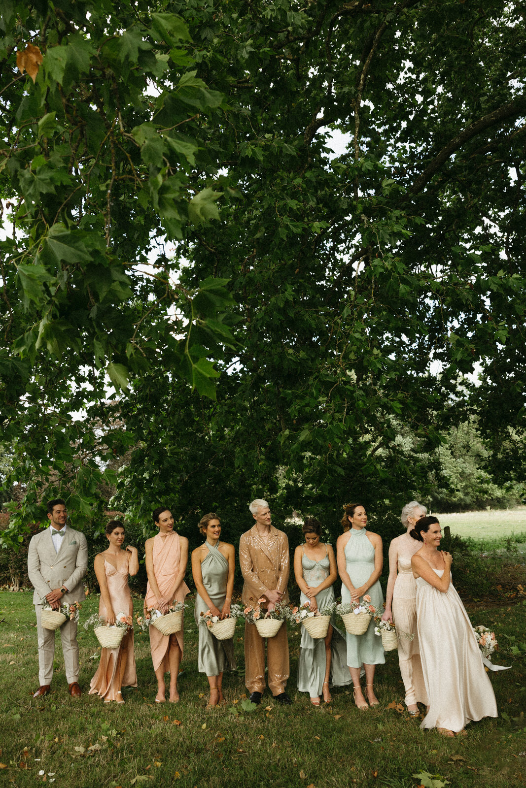 Bridesmaids holding floral baskets under oak tree