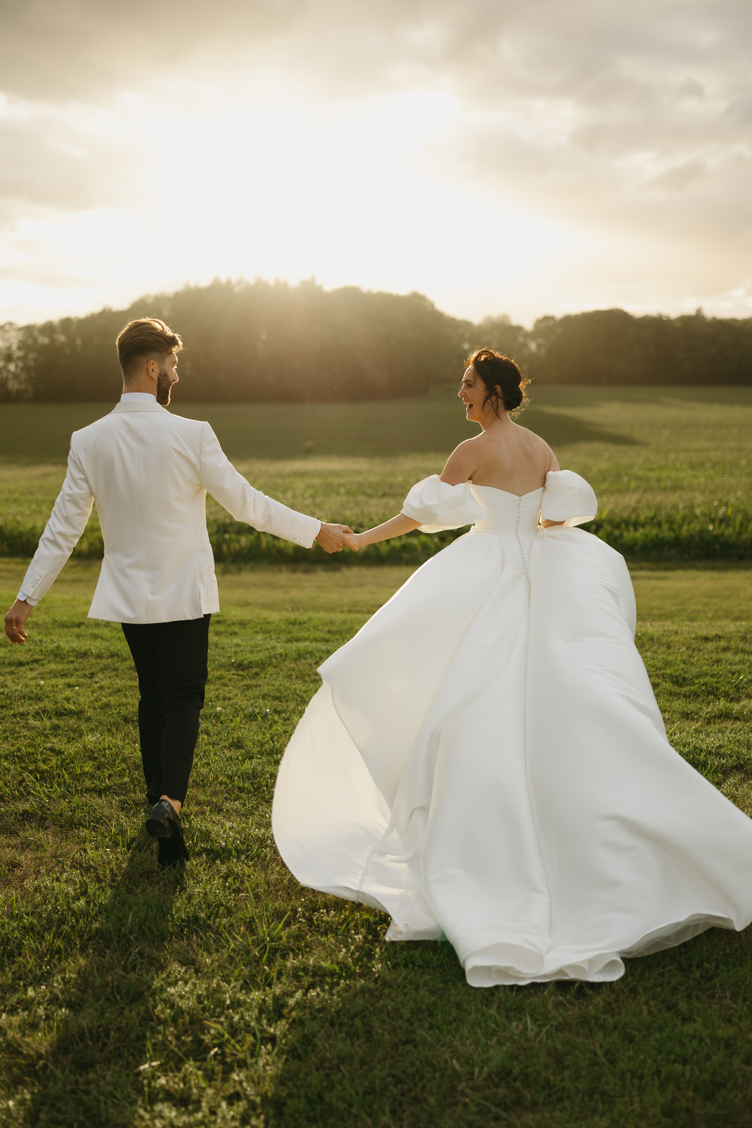 Bride and Groom running into the sunset holding hands and laughing
