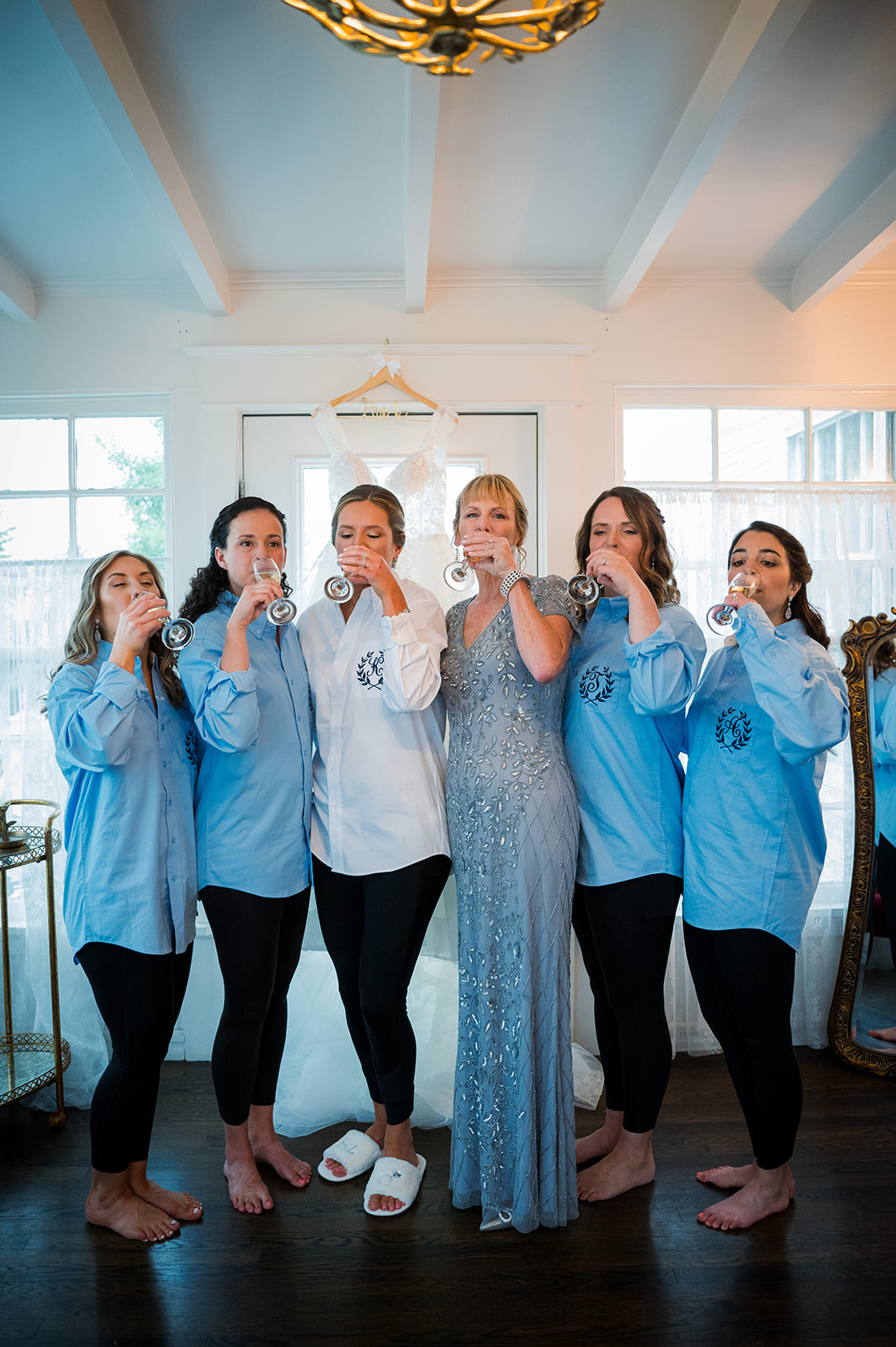 Bride shares sip of champagne with her bridesmaids who are all dressed in pajamas.